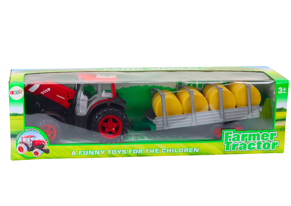 Velký zemědělský traktor s přívěsem a balíky sena červený