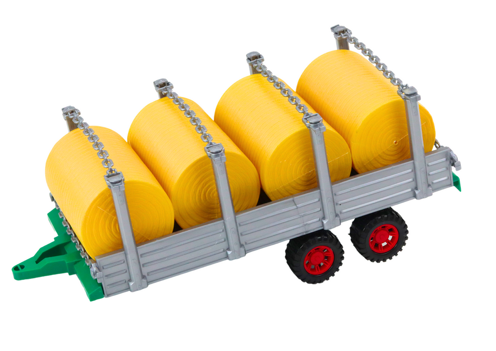 Velký zemědělský traktor s přívěsem a balíky sena červený